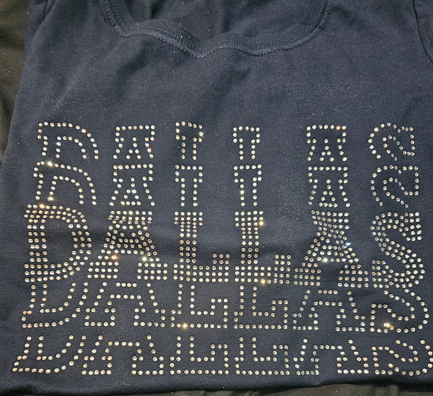 Black shirt with 'DALLAS' text in rhinestones on a dark background